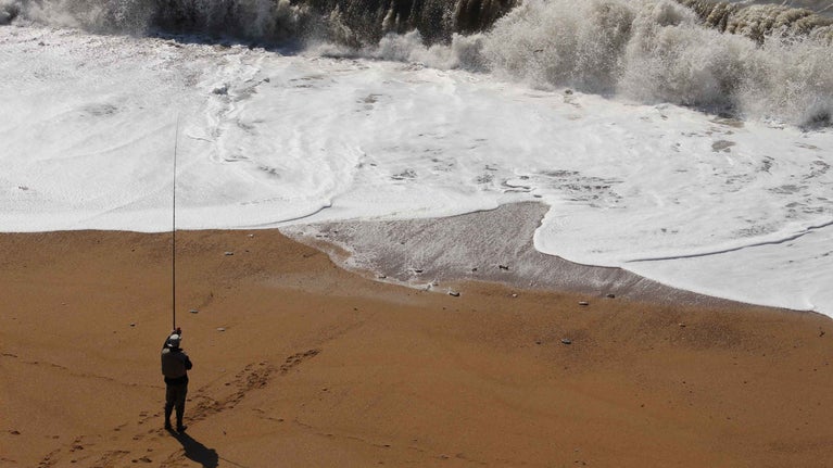 A man fishing on Hive Beach at Burton Bradstock, Dorset